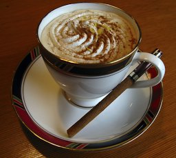 A cup of cappuccino with a cinnamon stick